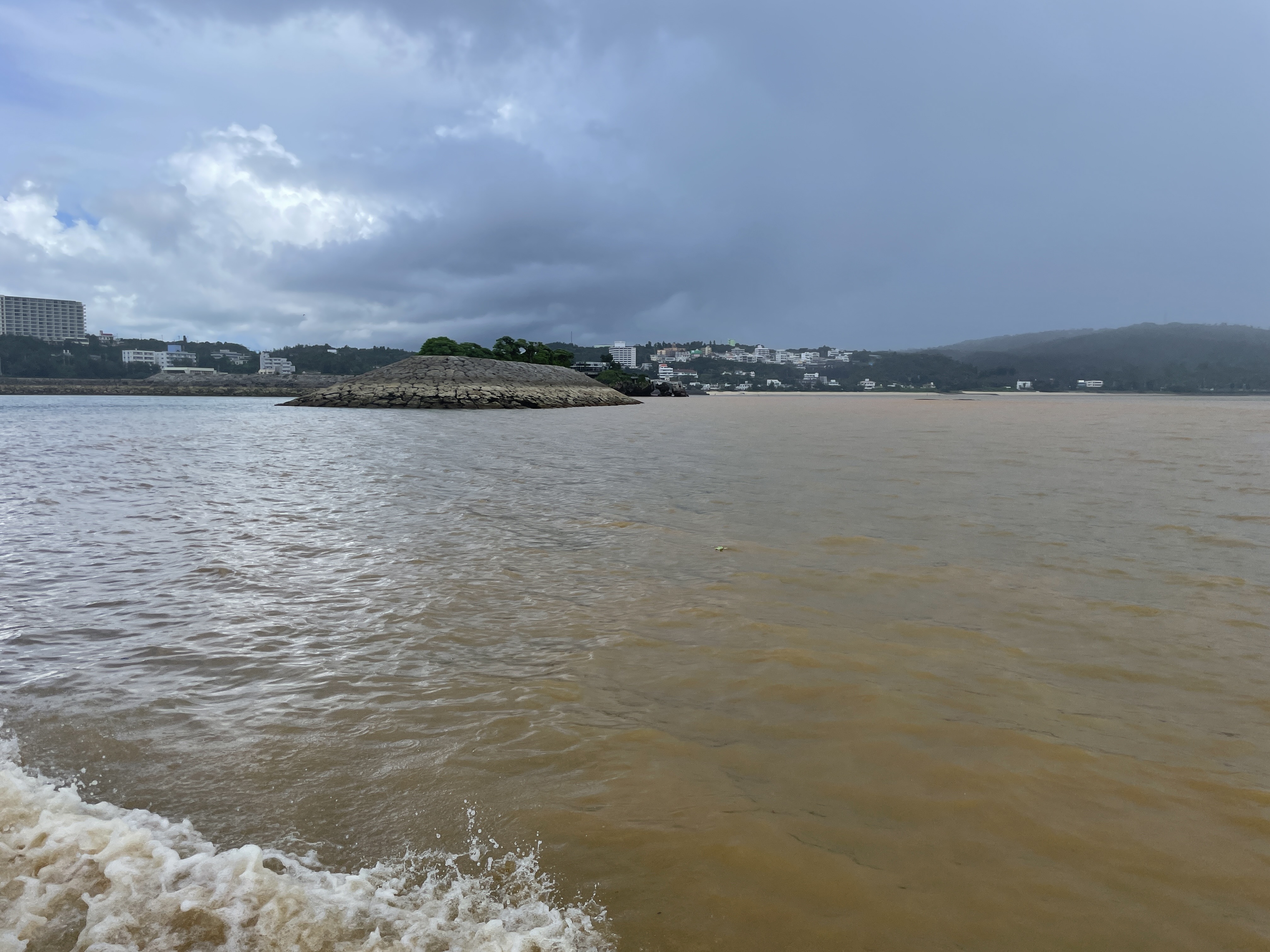 沖縄恩納村の湾で赤土が海に広がり、全体が茶色く濁っている様子（大雨後の撮影）