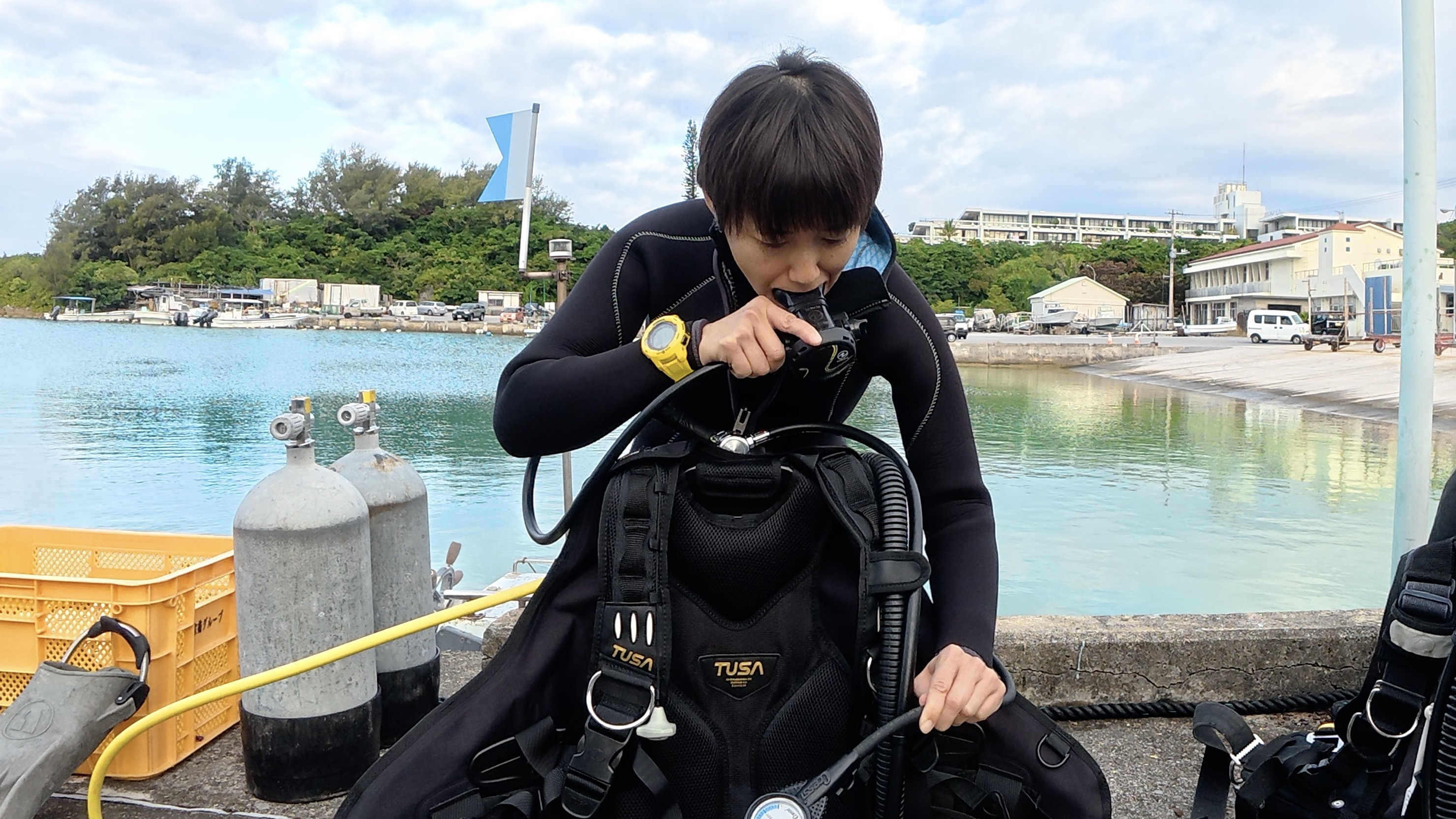 沖縄・恩納村の港で器材セッティングを確認するDM候補生(レギュレーターとBCD)