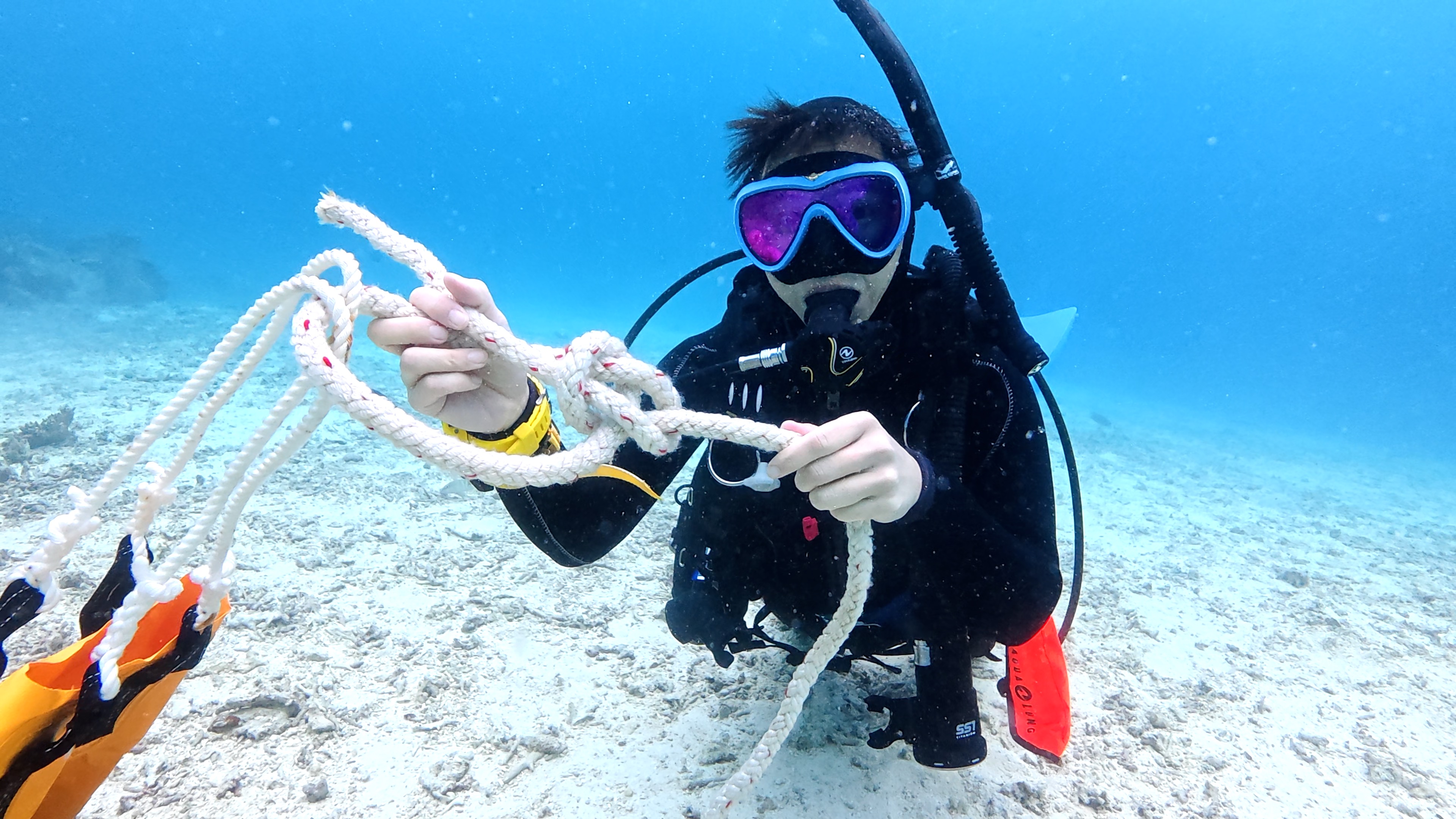 沖縄・恩納村の海中でダイバーがシグナルフロート（SMB）のロープを手元で管理している様子